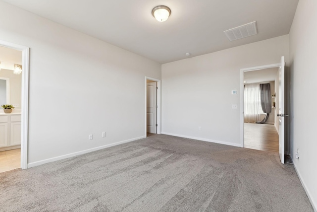 unfurnished bedroom featuring carpet floors, baseboards, visible vents, and ensuite bathroom