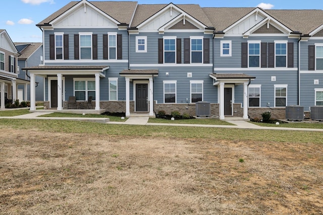 view of property with board and batten siding, cooling unit, and a front yard