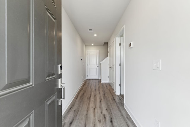 corridor with light wood finished floors, visible vents, baseboards, and recessed lighting