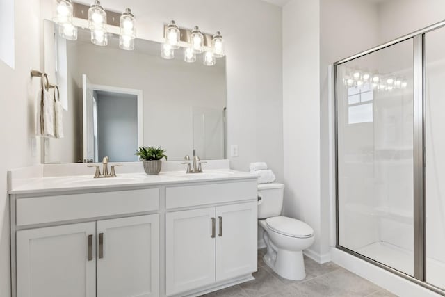 bathroom featuring toilet, a stall shower, a sink, and tile patterned floors