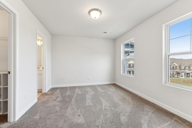 empty room featuring carpet, visible vents, and baseboards