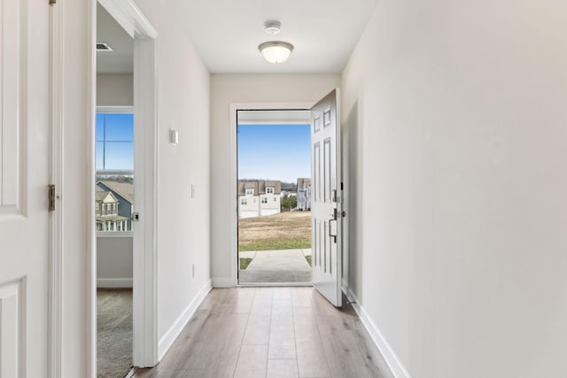 doorway to outside featuring light wood-style flooring and baseboards