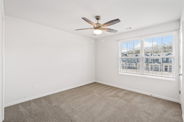 carpeted spare room with a ceiling fan, visible vents, and baseboards