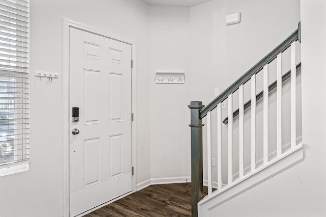 foyer featuring dark wood-style flooring, stairway, and baseboards