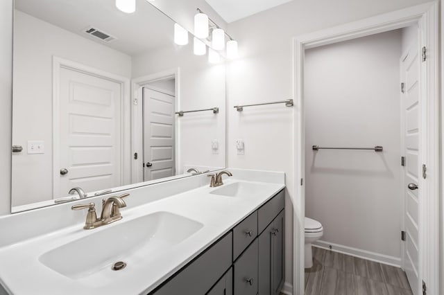 full bath with visible vents, a sink, toilet, and double vanity