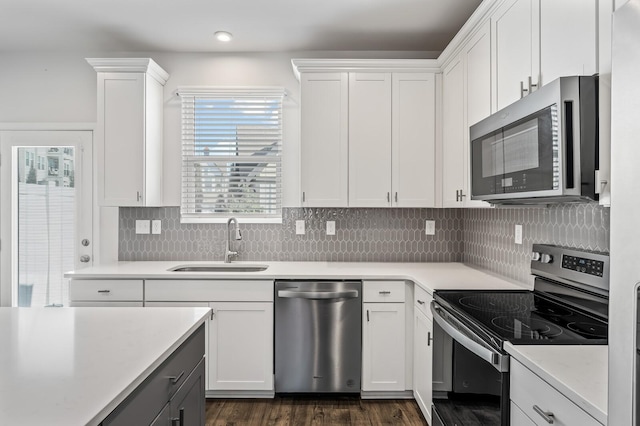 kitchen with tasteful backsplash, white cabinets, appliances with stainless steel finishes, light countertops, and a sink