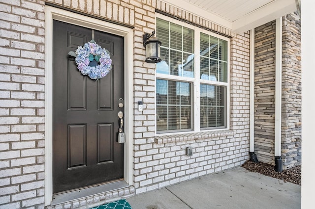 entrance to property with a porch and brick siding