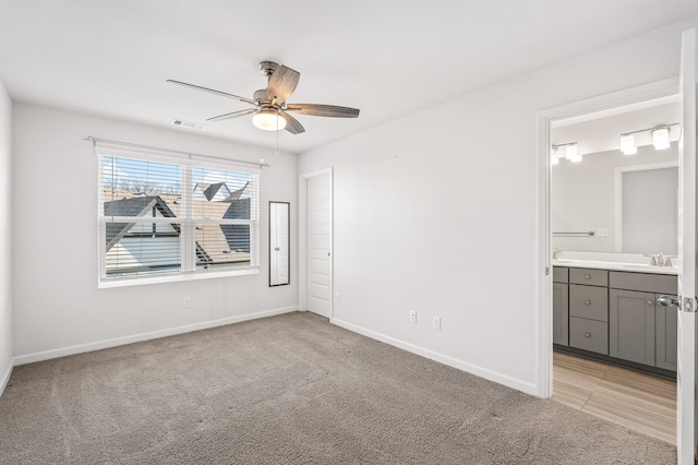 unfurnished bedroom with baseboards, visible vents, connected bathroom, light colored carpet, and a sink