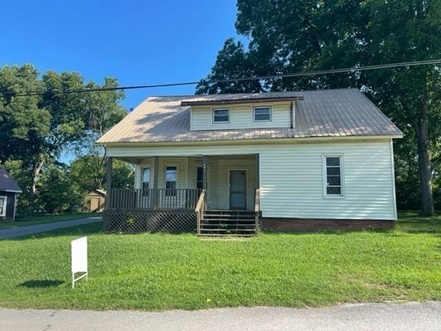 bungalow featuring covered porch, metal roof, and a front yard