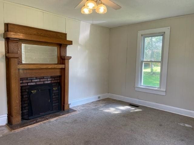 unfurnished living room featuring carpet, a fireplace, visible vents, ceiling fan, and baseboards