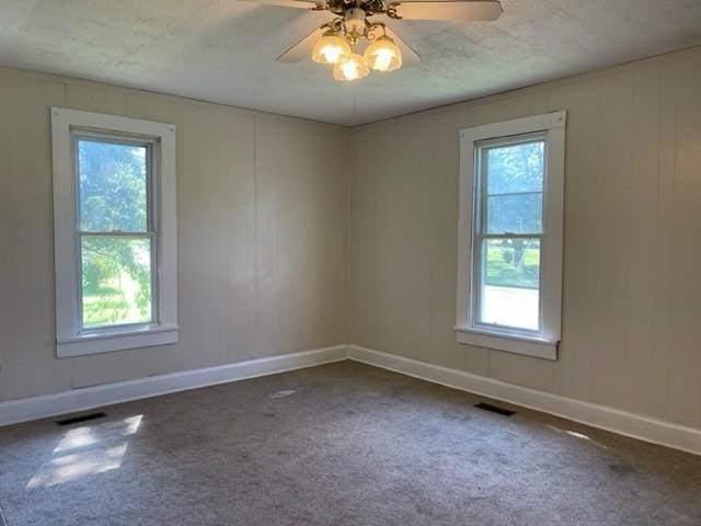 spare room featuring carpet floors, visible vents, and baseboards