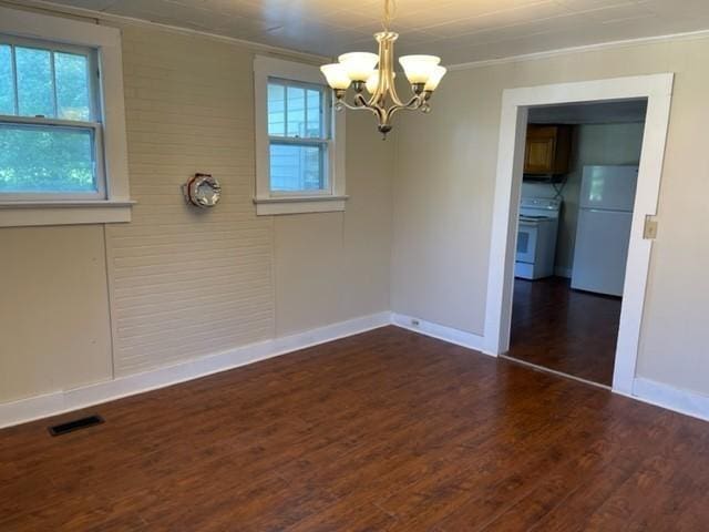 spare room featuring ornamental molding, wood finished floors, visible vents, and a healthy amount of sunlight