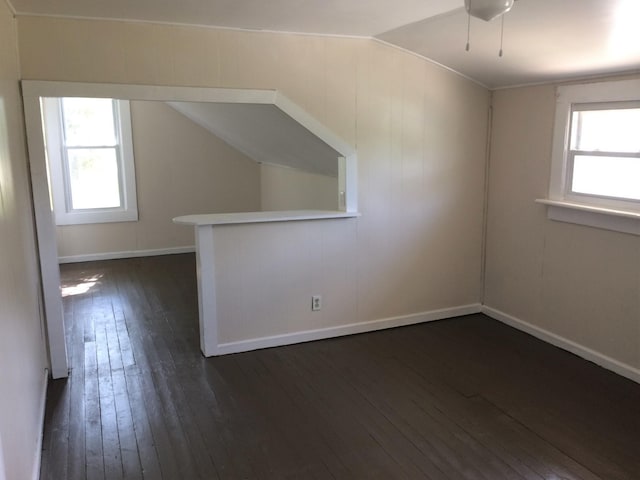 additional living space featuring vaulted ceiling, dark wood finished floors, and baseboards