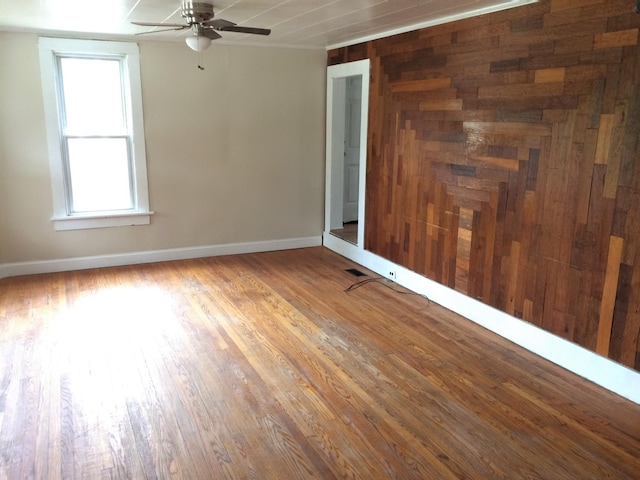 empty room with ceiling fan, wood finished floors, and baseboards