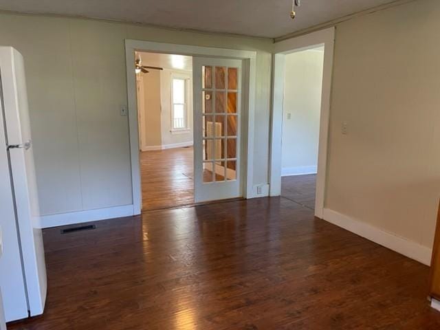 spare room featuring wood finished floors, visible vents, and baseboards