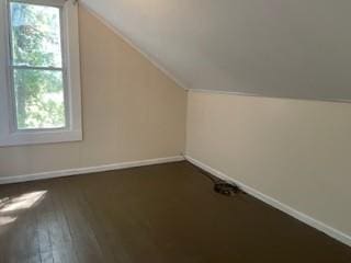 bonus room with baseboards, vaulted ceiling, and dark wood-type flooring