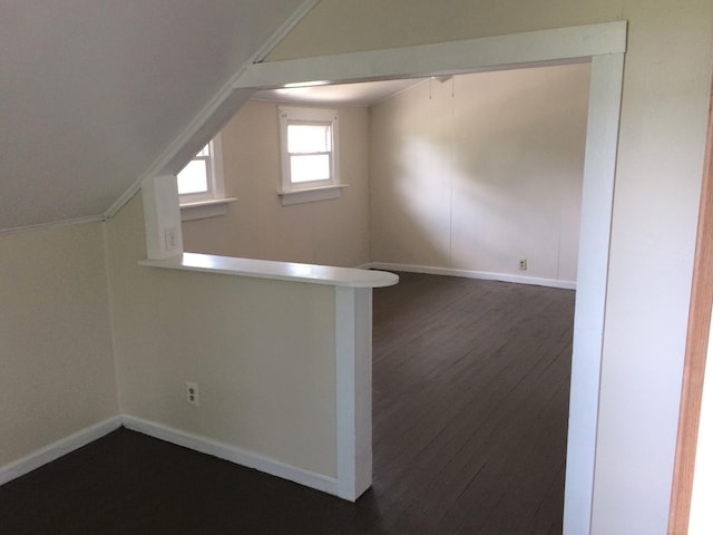 additional living space with lofted ceiling, dark wood-style floors, and baseboards