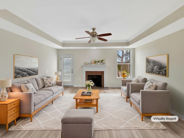 living room featuring a raised ceiling, crown molding, and light wood finished floors