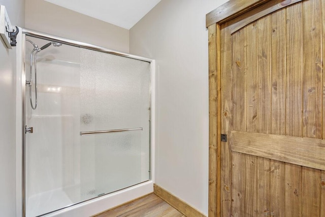 bathroom with a shower stall, baseboards, and wood finished floors