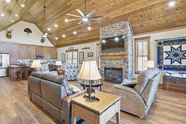 living area featuring high vaulted ceiling, a stone fireplace, light wood-style flooring, and wood ceiling