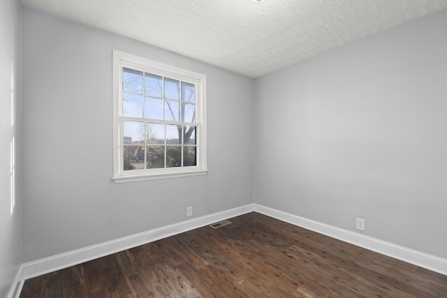 unfurnished room featuring a textured ceiling, dark wood-type flooring, visible vents, and baseboards