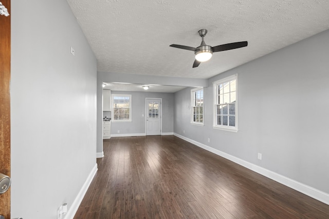 unfurnished living room with baseboards, a textured ceiling, and hardwood / wood-style floors