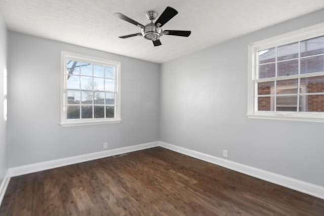 unfurnished room with ceiling fan, dark wood-style flooring, and baseboards