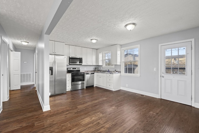 kitchen featuring dark wood-type flooring, visible vents, baseboards, white cabinets, and appliances with stainless steel finishes