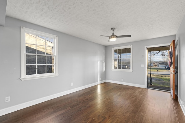 spare room with a textured ceiling, ceiling fan, dark wood-style flooring, and baseboards