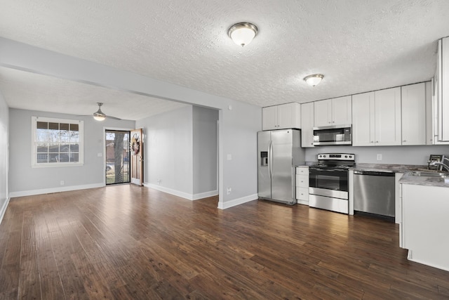 kitchen with stainless steel appliances, open floor plan, white cabinets, and dark wood-style floors