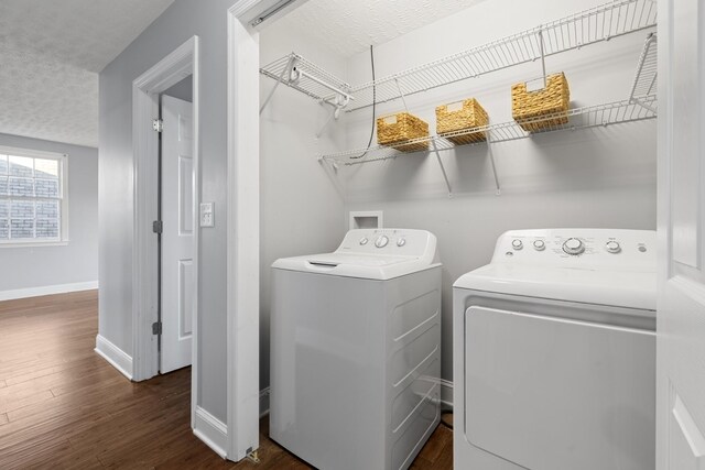 washroom with a textured ceiling, washing machine and clothes dryer, dark wood finished floors, and baseboards