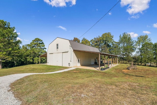 exterior space with metal roof, a patio, a barn, a gambrel roof, and a yard