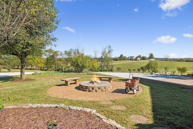 view of community with a rural view, a fire pit, and a yard