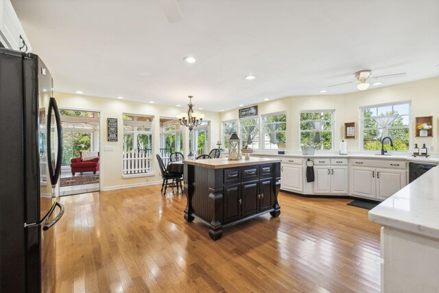 kitchen featuring light wood finished floors, black dishwasher, white cabinetry, and freestanding refrigerator