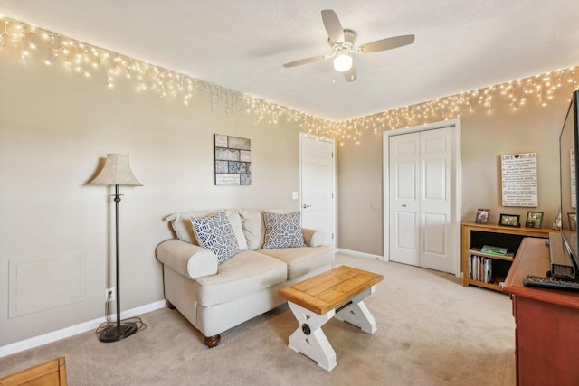 living room featuring light carpet, a ceiling fan, and baseboards