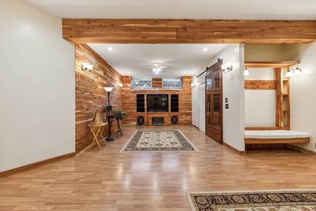 interior space with a barn door, wood finished floors, and wooden walls