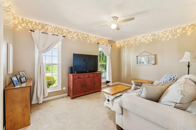 living room featuring light colored carpet, ceiling fan, and baseboards