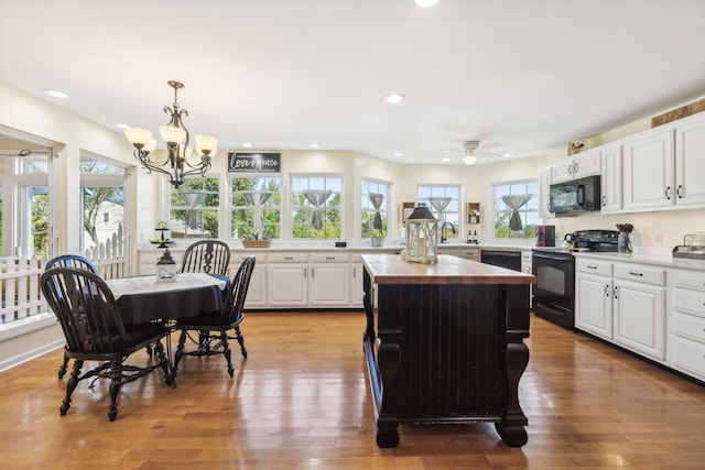 kitchen featuring black appliances, butcher block counters, plenty of natural light, and light wood-style floors