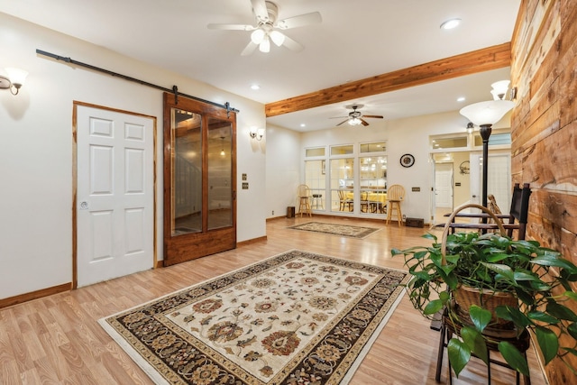 foyer with a barn door, baseboards, ceiling fan, wood finished floors, and beamed ceiling