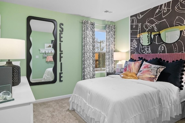 carpeted bedroom with an accent wall, visible vents, and baseboards