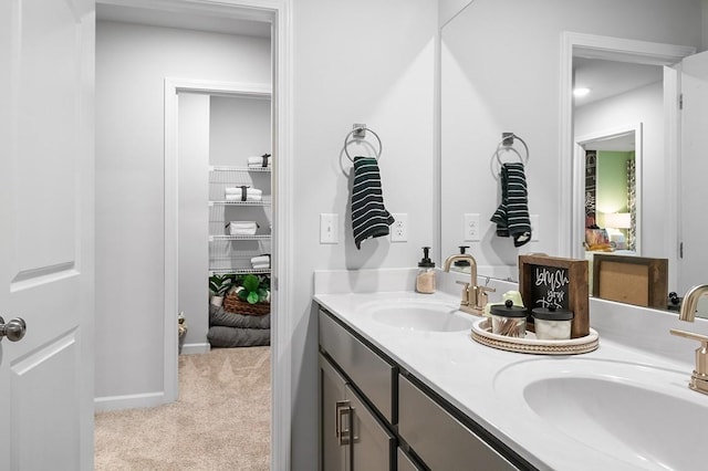 bathroom featuring a sink, baseboards, and double vanity