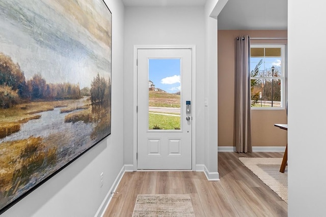 entryway with light wood-type flooring, a wealth of natural light, and baseboards