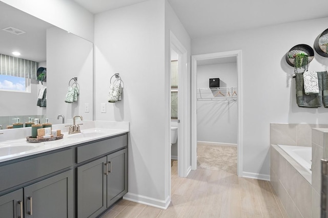 bathroom with a garden tub, double vanity, a sink, and visible vents