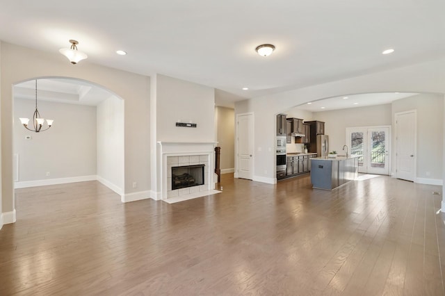 unfurnished living room featuring dark wood-style flooring, a fireplace, a sink, and baseboards