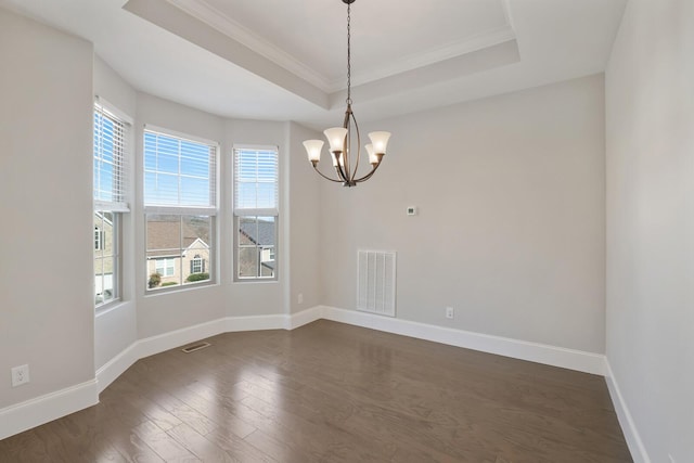 spare room featuring dark wood-style floors, a raised ceiling, visible vents, and baseboards