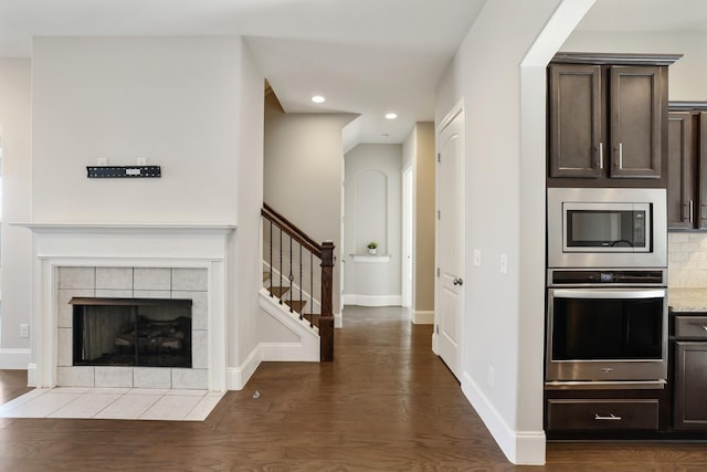 kitchen with decorative backsplash, appliances with stainless steel finishes, dark brown cabinets, wood finished floors, and baseboards