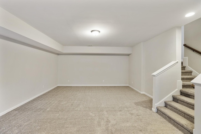 below grade area featuring carpet floors, baseboards, and stairs