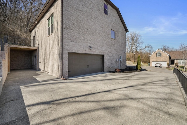 view of home's exterior featuring a garage, brick siding, and driveway