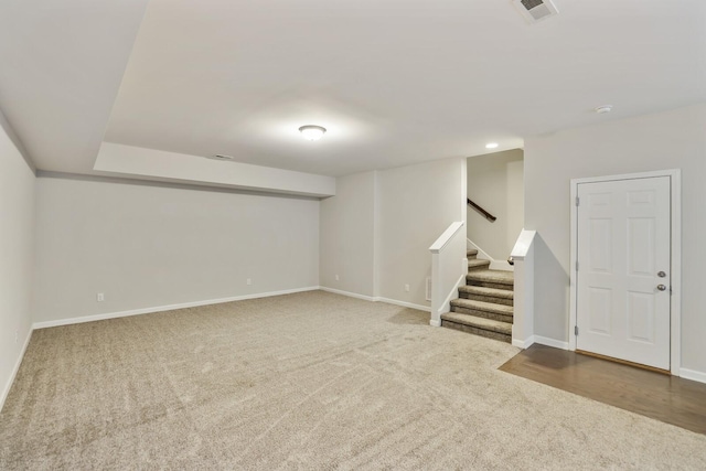 finished basement featuring stairway, carpet, visible vents, and baseboards