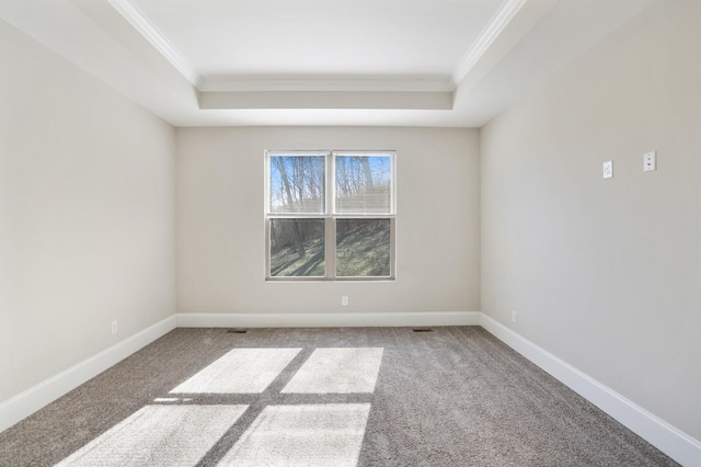 unfurnished room featuring ornamental molding, a raised ceiling, and baseboards